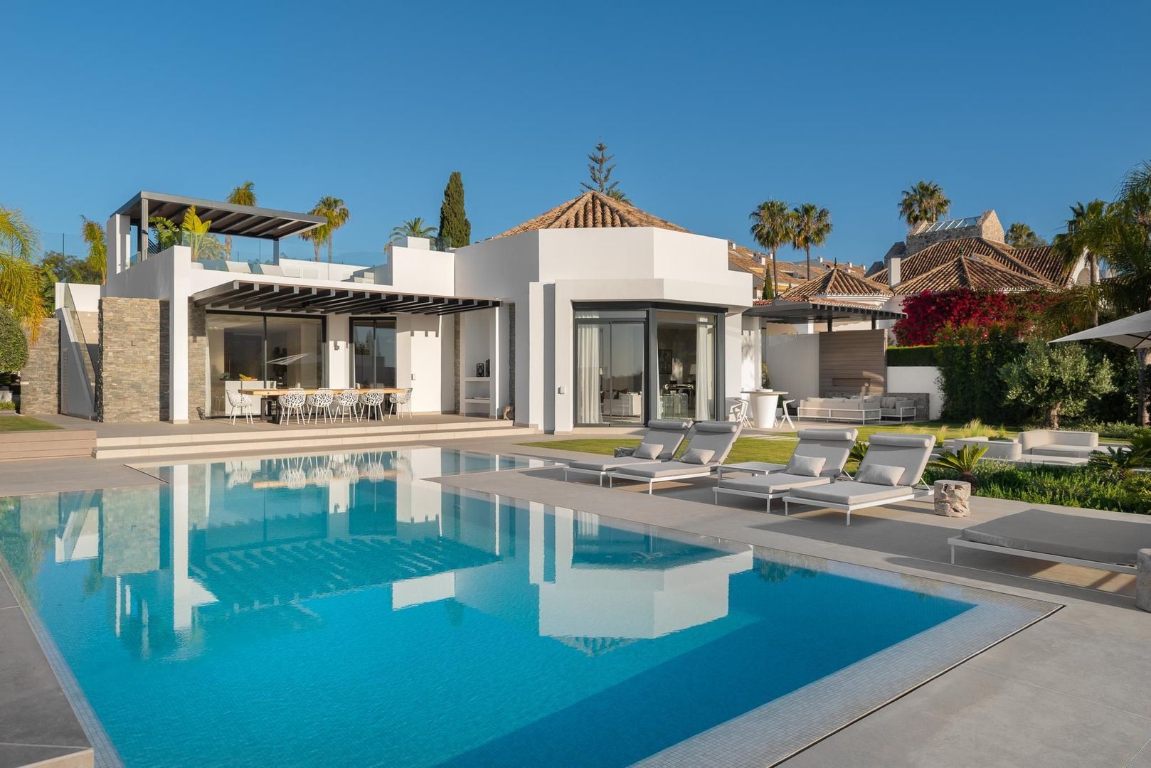 Main pool façade of Villa Aquila with Mediterranean rooflines, white walls and generous outdoor living terraces