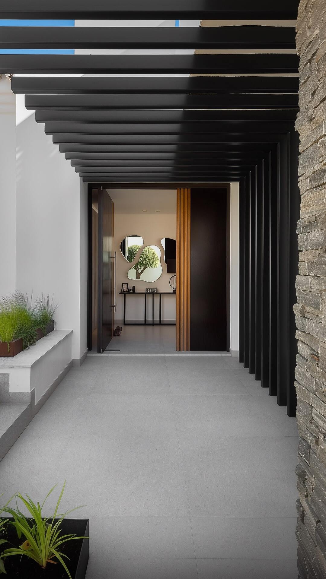 Vertical entrance sequence of Villa Aquila emphasizing the stone wall, linear pergola and warm doorway lighting