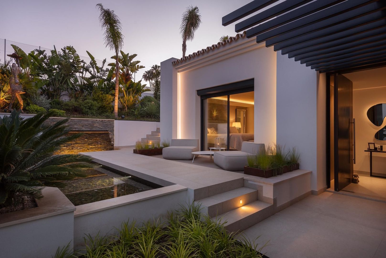 Twilight terrace angle of Villa Aquila with planted steps, illuminated outdoor lounge and warm Mediterranean ambience