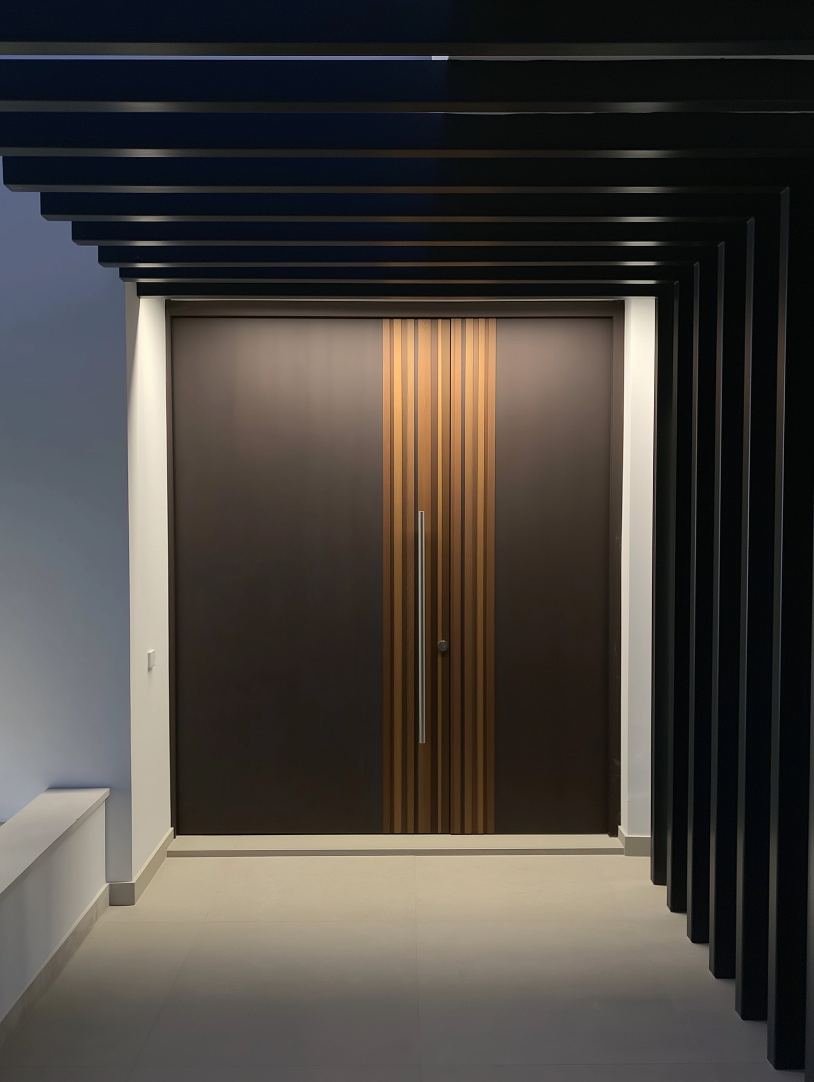 Primary entrance doorway at Villa Aquila framed by dark pergola structure and warm indirect lighting