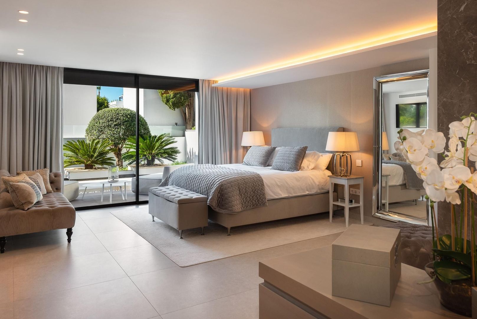 Lounge interior of Villa Aquila with large sliding openings, calm neutral materials and garden-facing living space