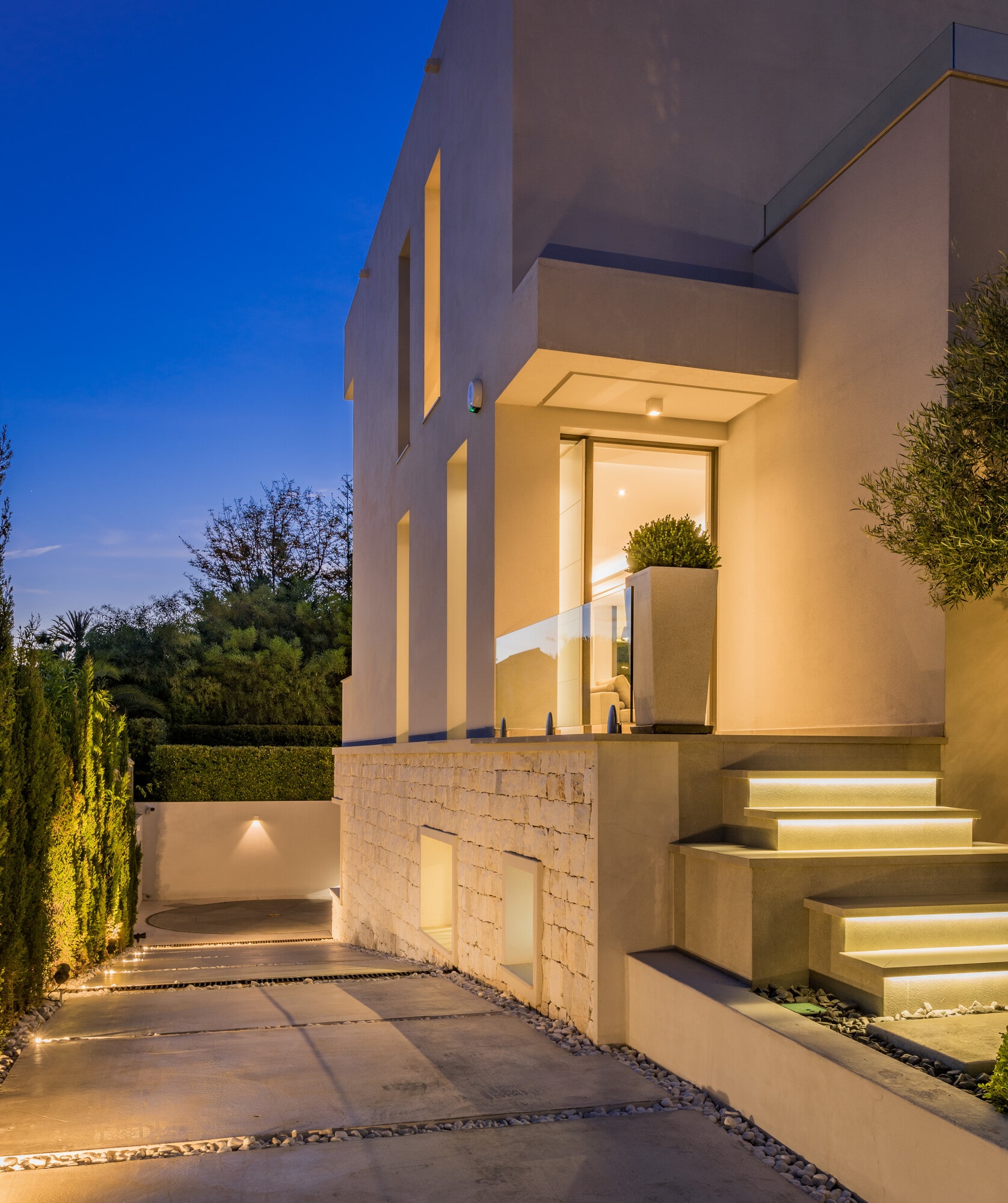 Exterior arrival view at Villa Australia with warm uplighting, sculpted steps and contemporary façade composition