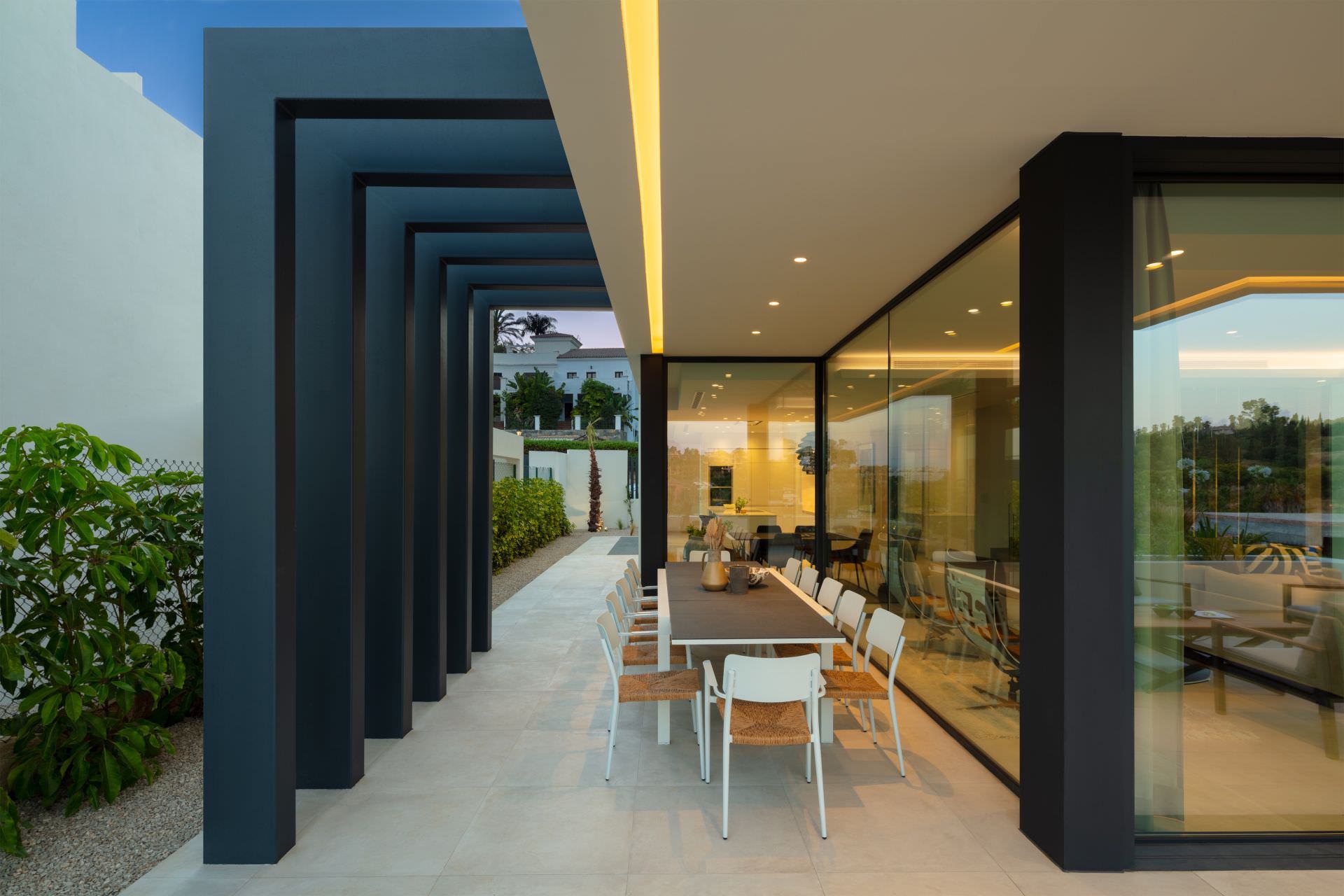 Covered outdoor terrace at BELFRY with pergola rhythm, dining area and seamless interior connection