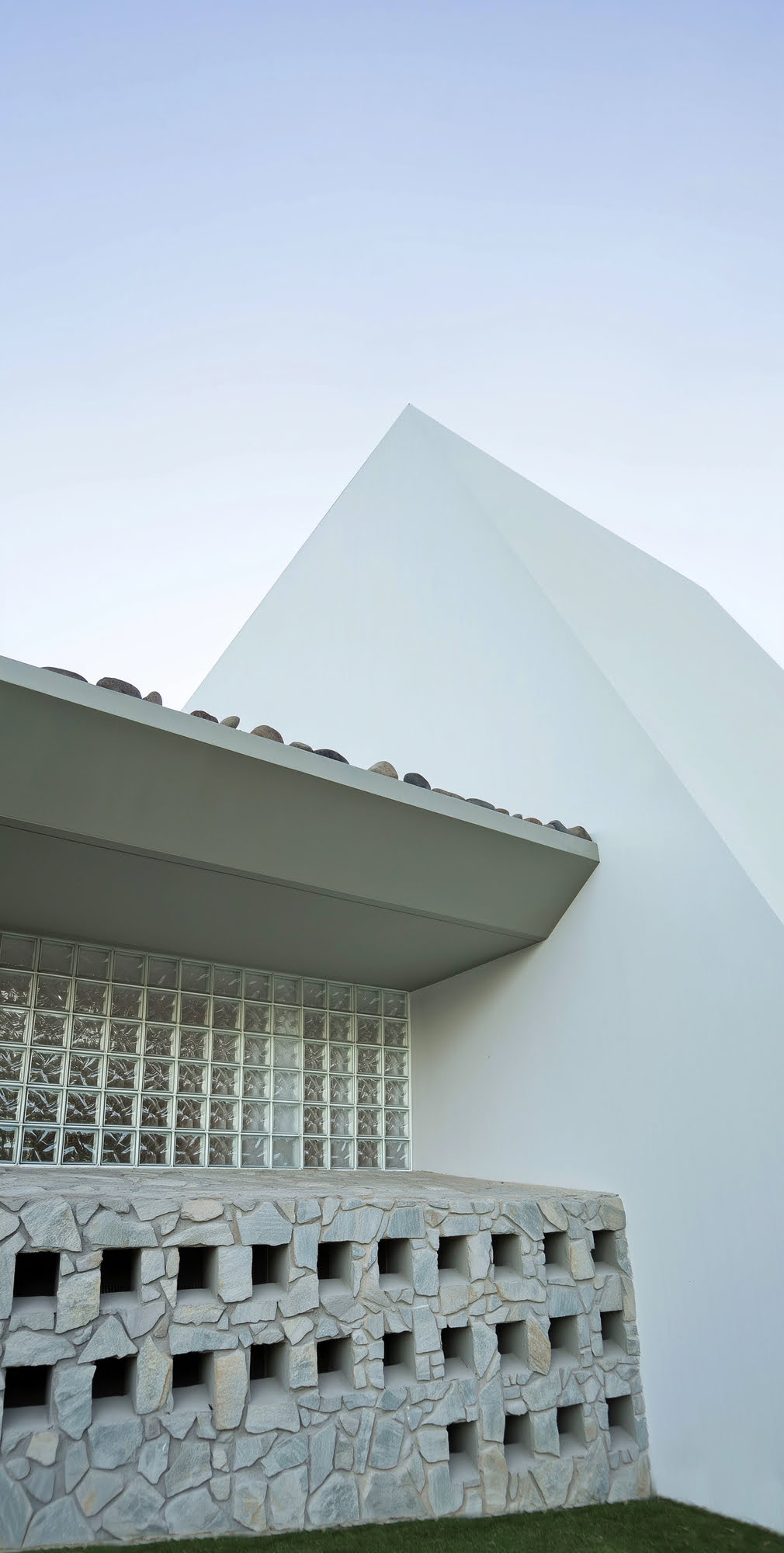 Architectural close-up of the clubhouse roofline, glass block wall and sharp white geometry