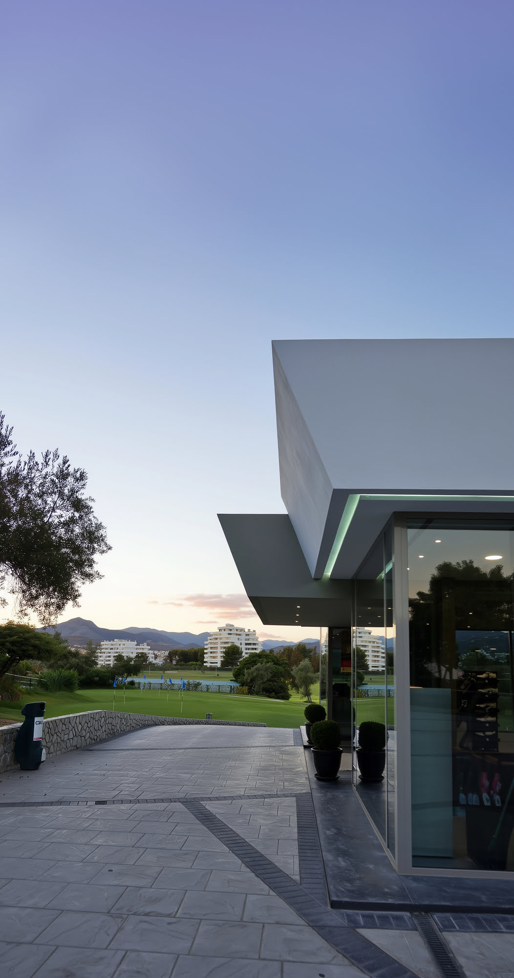 Dusk view of the clubhouse access and projecting white roof with the golf landscape in the background