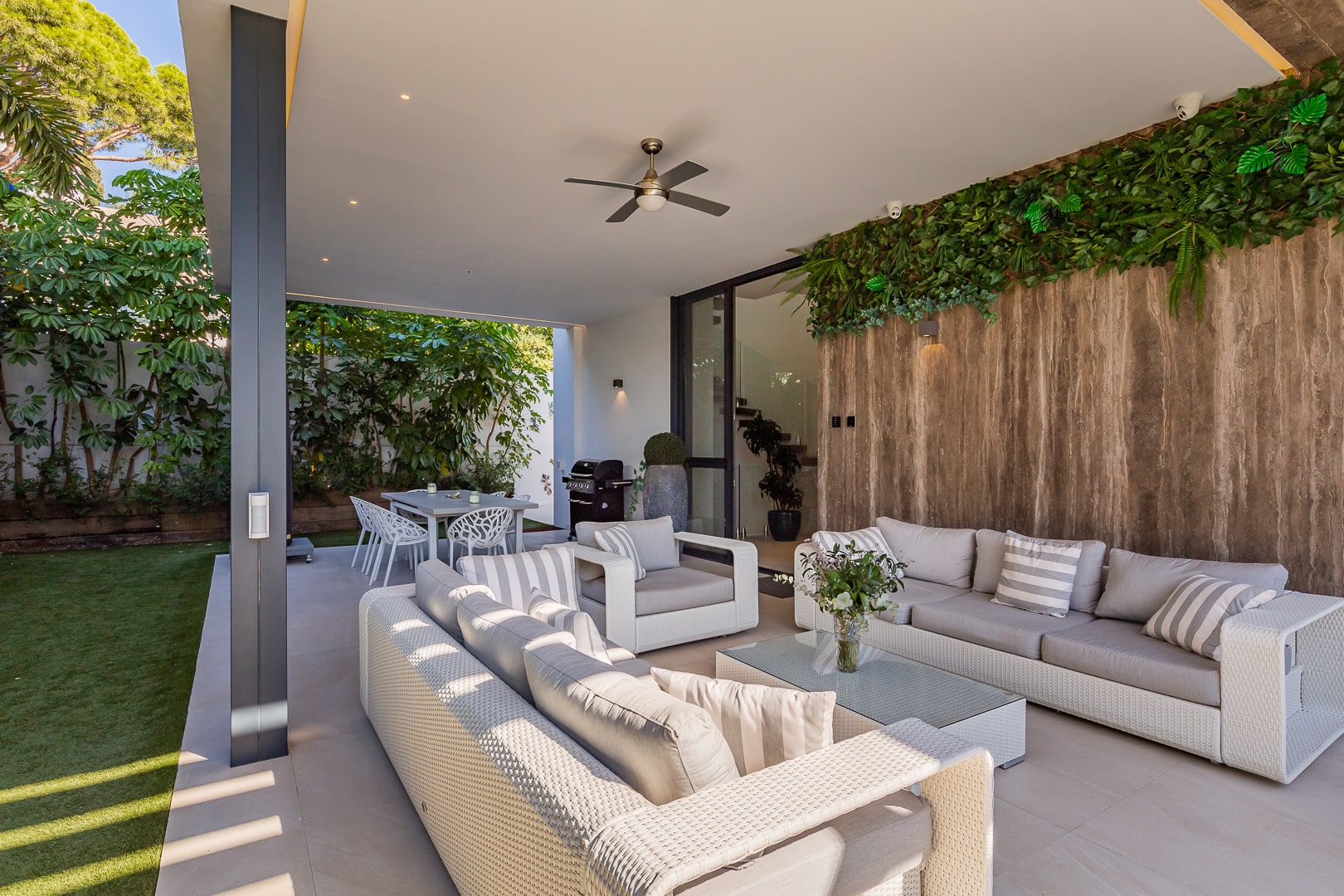 Covered outdoor lounge at DALÍ Villa with timber soffit, built-in seating and warm evening ambience