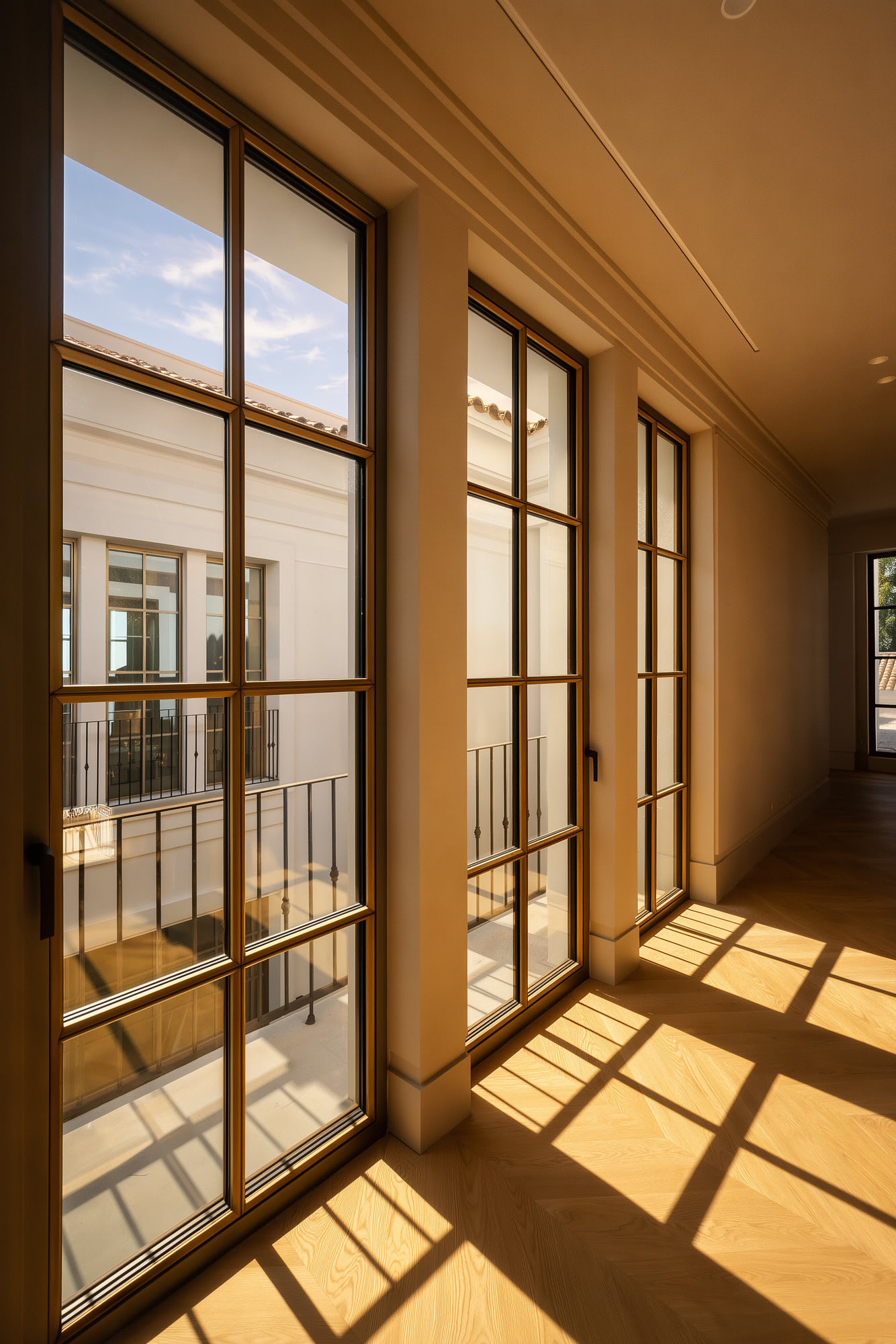 Sunlit corridor beside glazed openings at Villa Diva, emphasizing rhythm, light and classical proportion