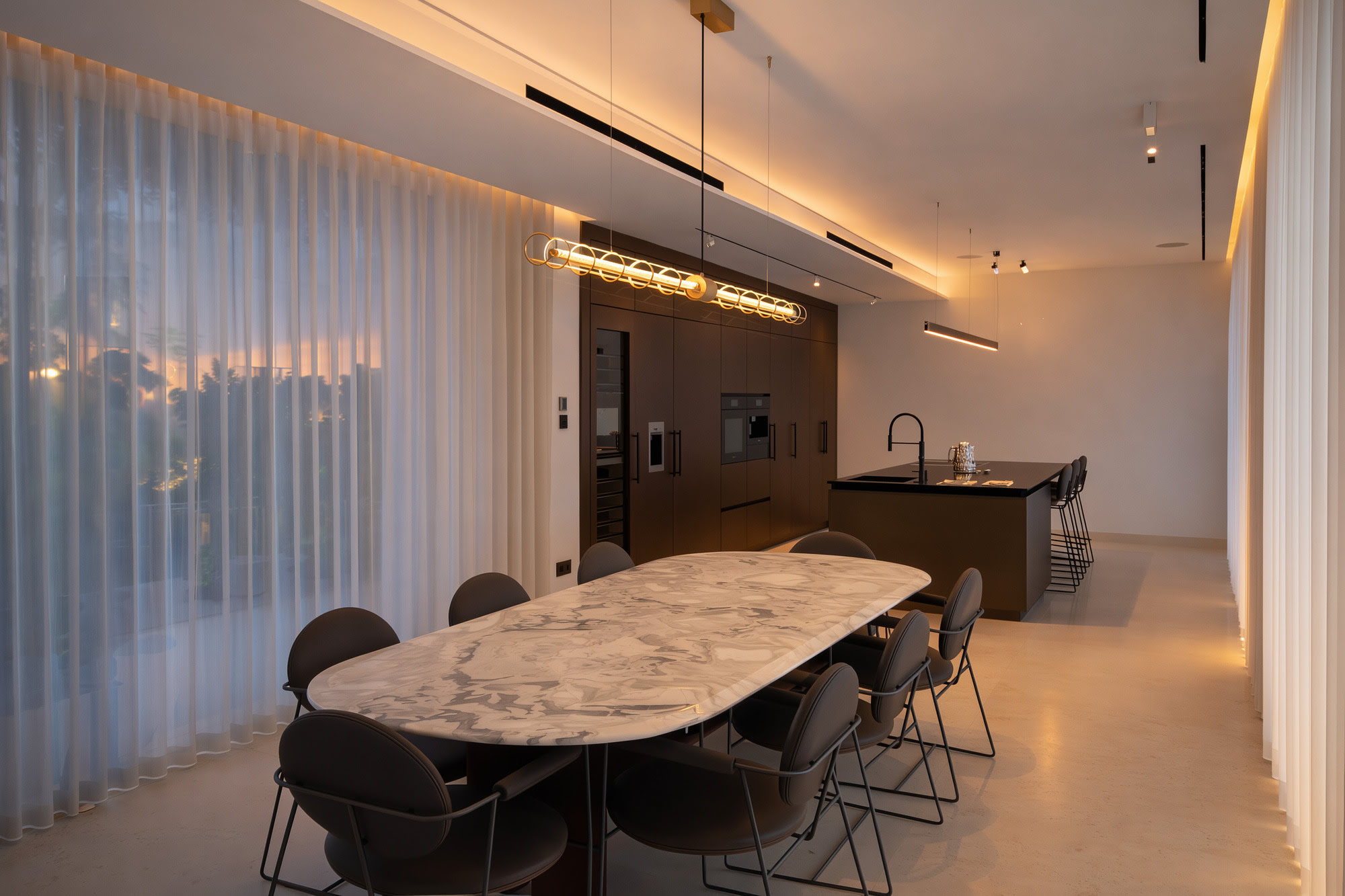 Dining area at Villa Inés with marble table, concealed ceiling lighting and elegant sheer curtains