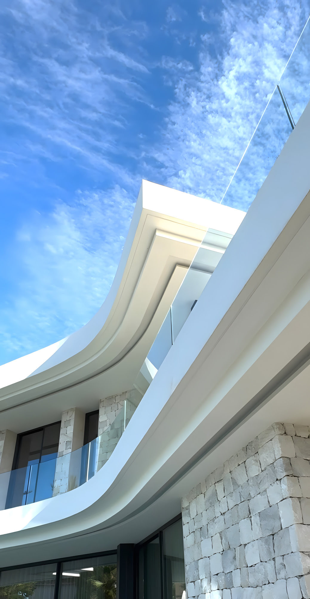 Architectural detail of the sweeping curved cornice and stone wall at M94 under Mediterranean sky