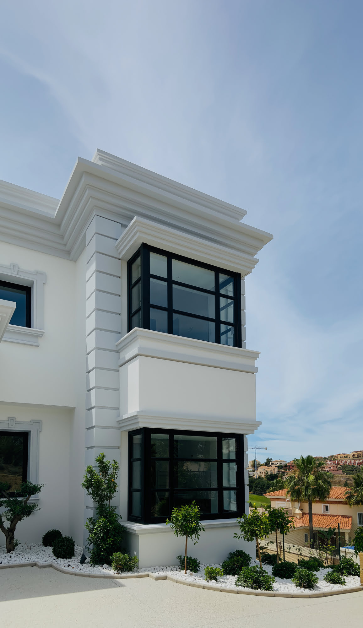 Corner view of Villa Mariselena highlighting classical mouldings, black-framed windows and landscaped entrance garden