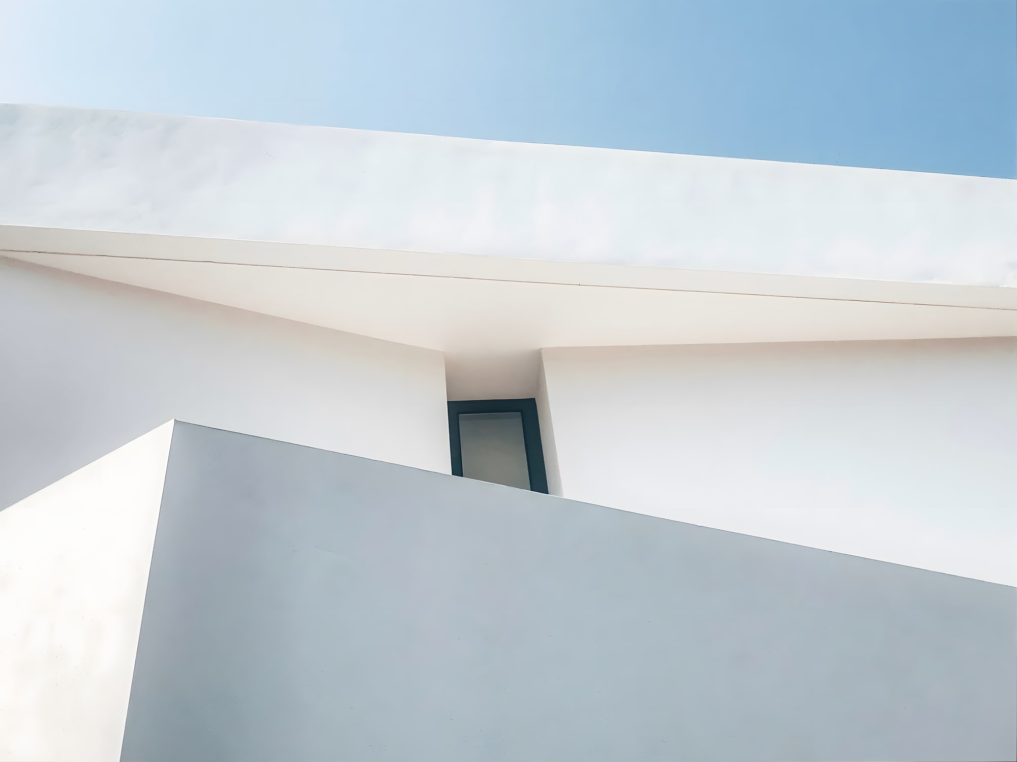Abstract façade crop of Villa Origami highlighting angular white planes and recessed glazing