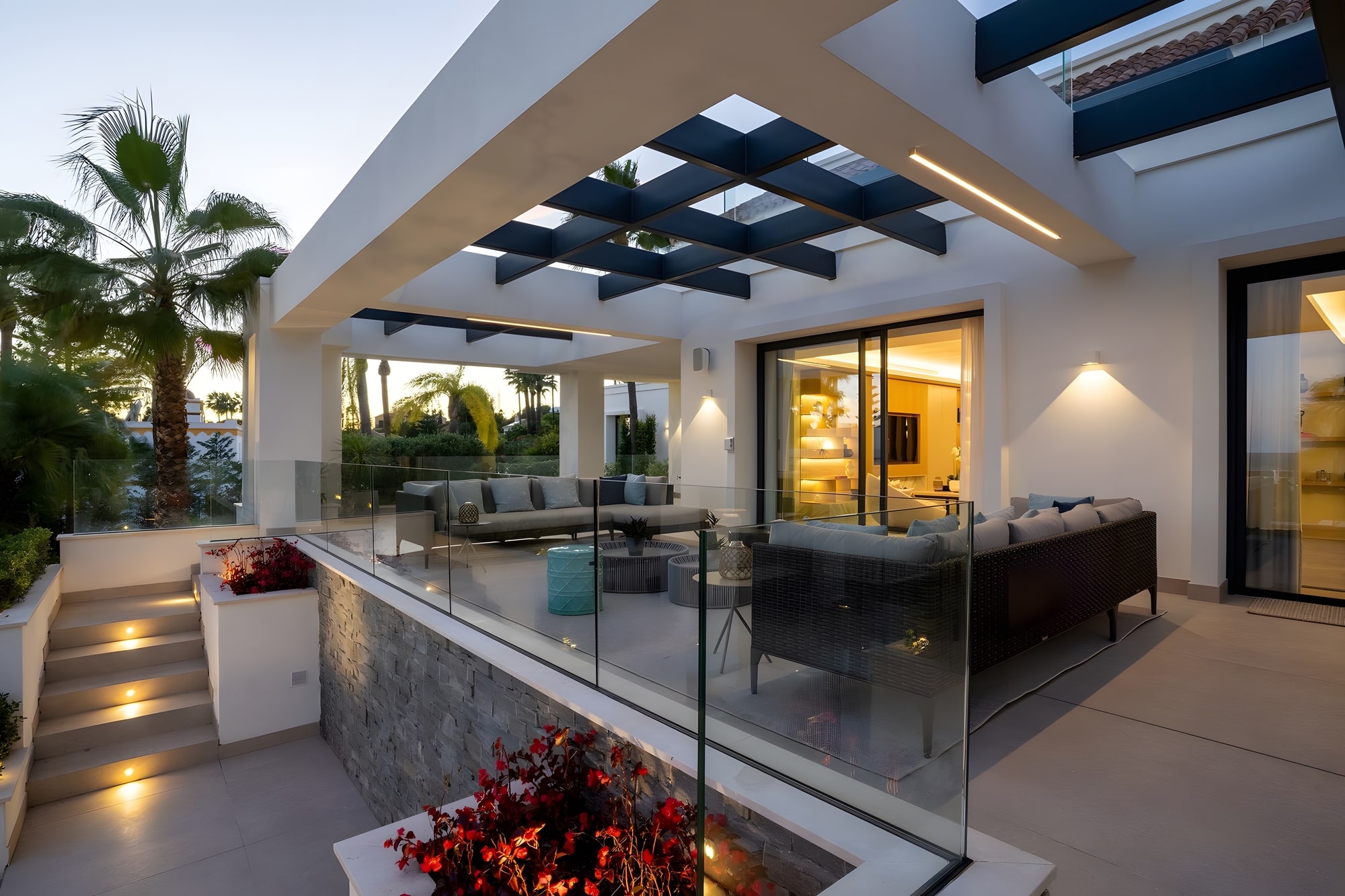Twilight exterior living terrace with fireplace, warm lighting and seamless indoor outdoor connection