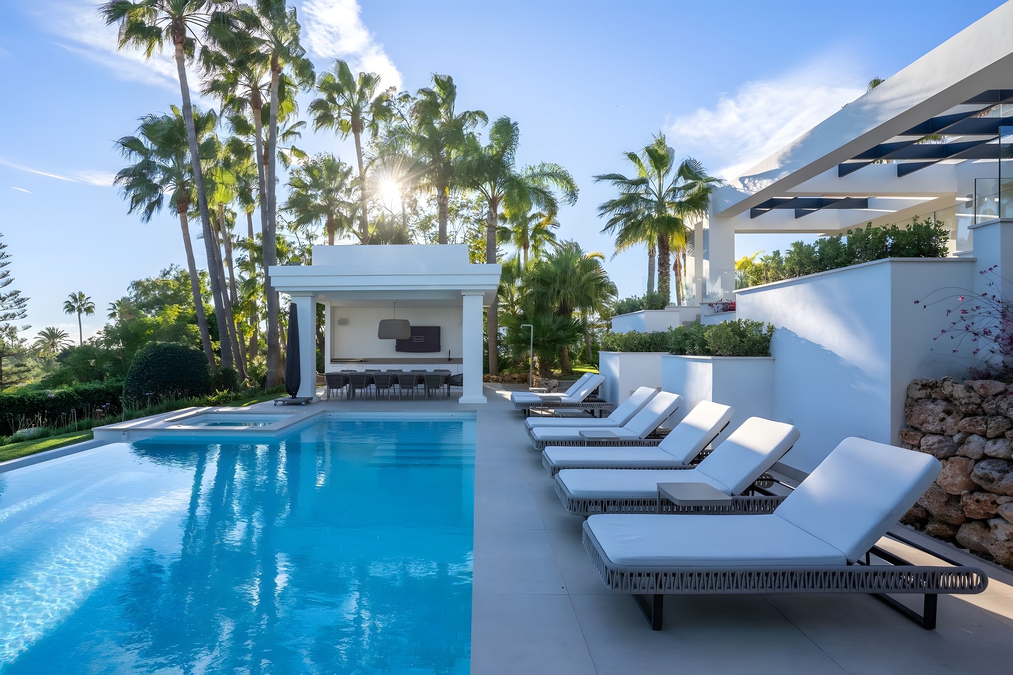 Infinity pool and main house composition with white architecture and tropical landscaping in Estepona