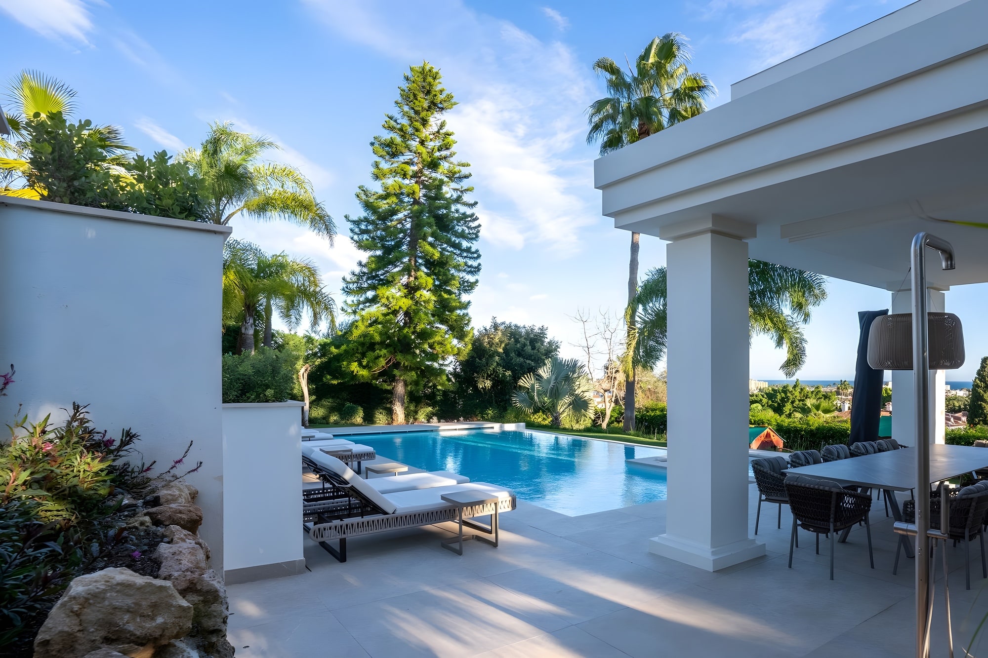 Poolside approach toward the covered terrace and outdoor living areas of this luxury villa in Estepona
