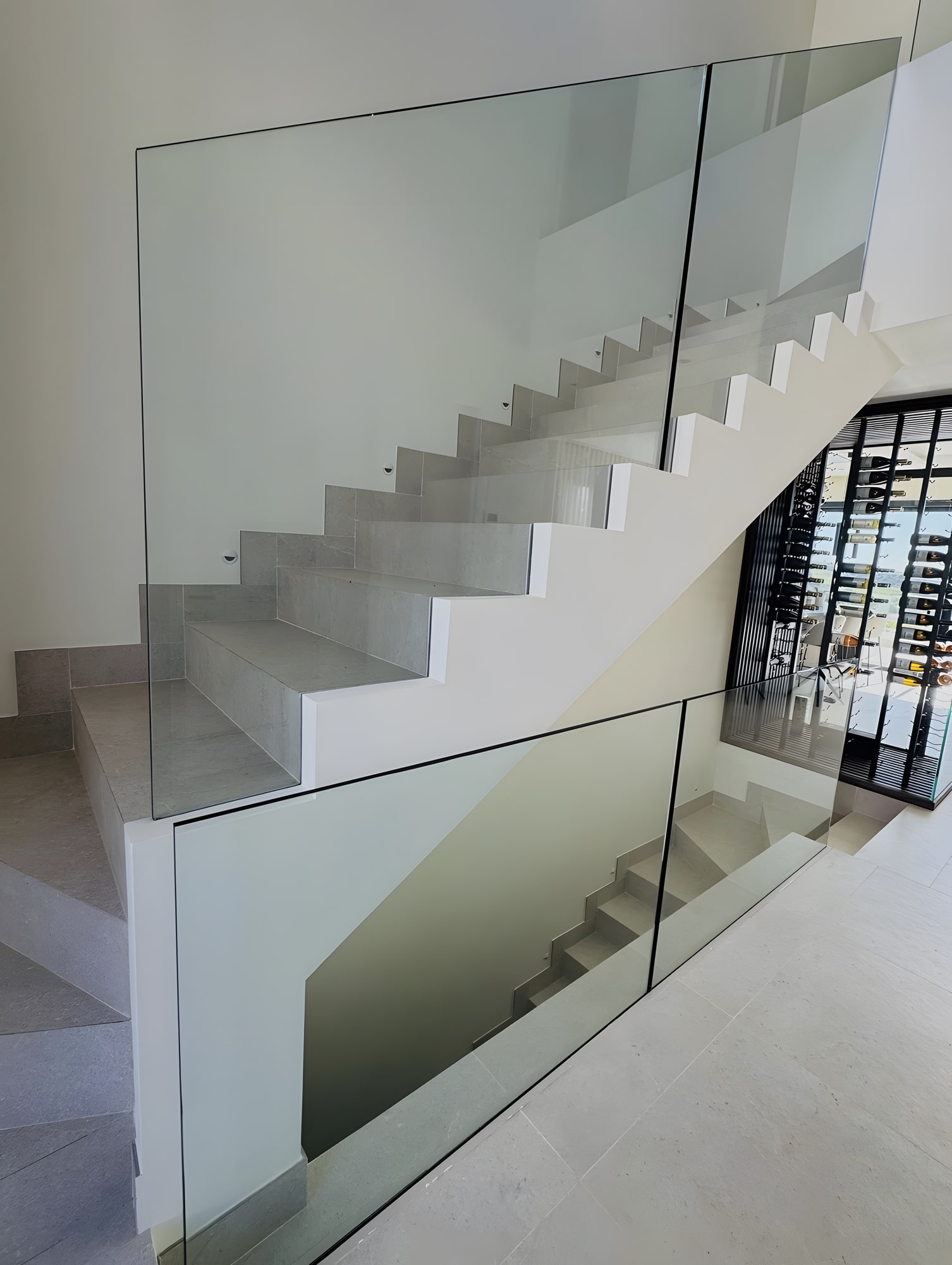 Minimalist staircase detail with glass balustrade and pale stone finishes