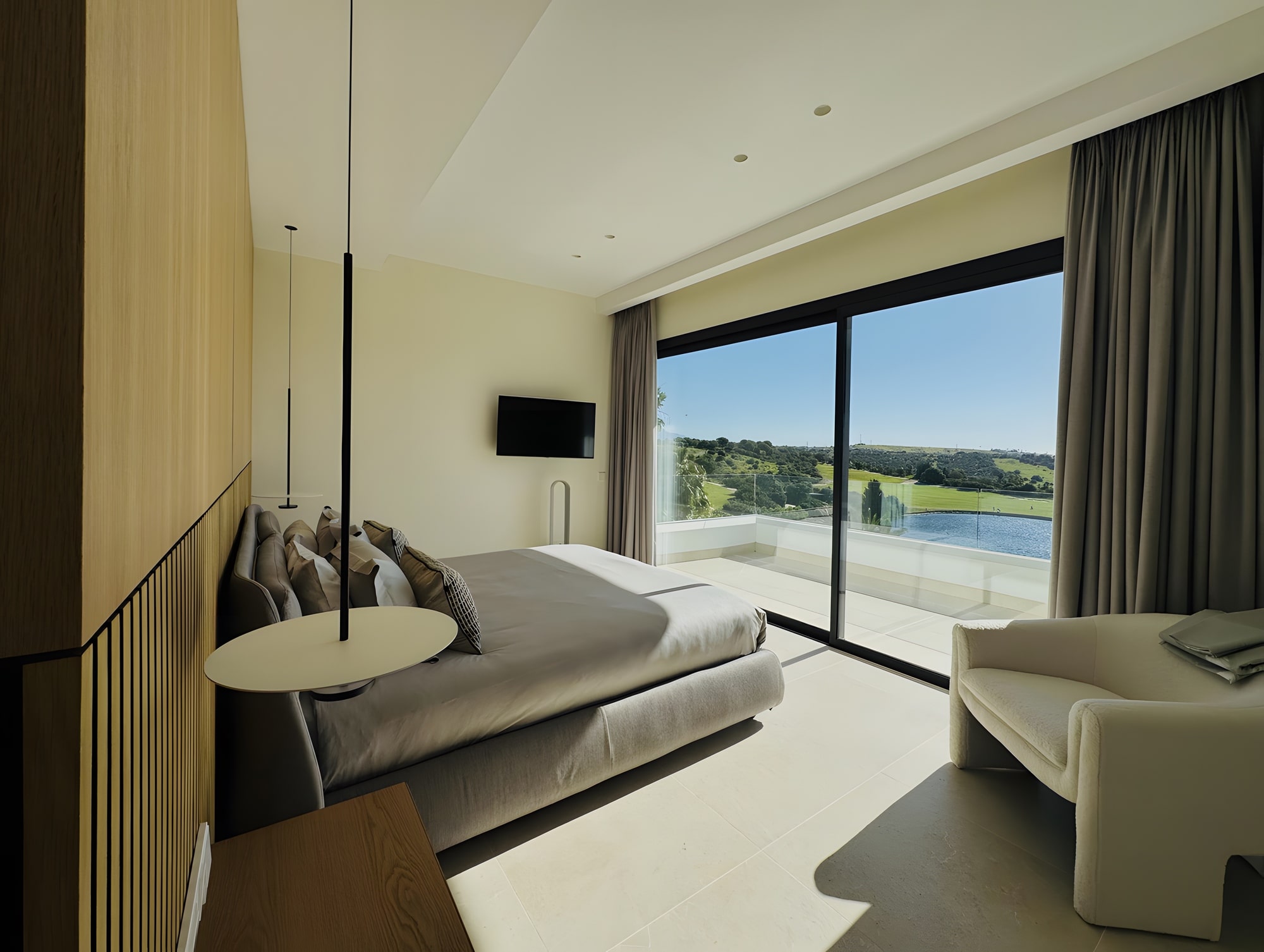 Primary bedroom with framed sea views, integrated desk and floor-to-ceiling glazing