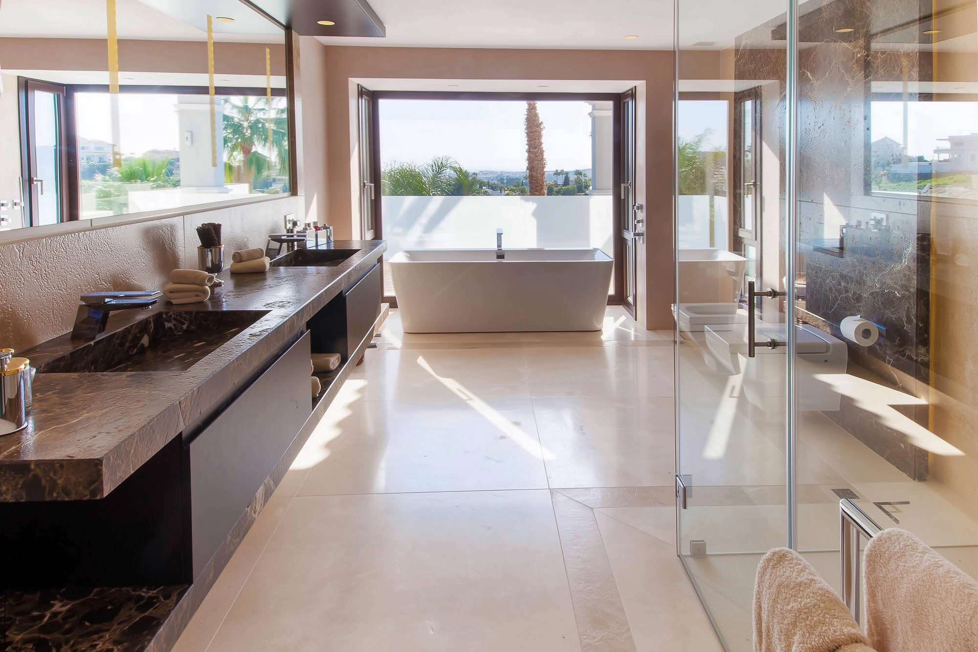 Bright bathroom and dressing area inside Villa Tanya with marble surfaces and garden-facing glazing