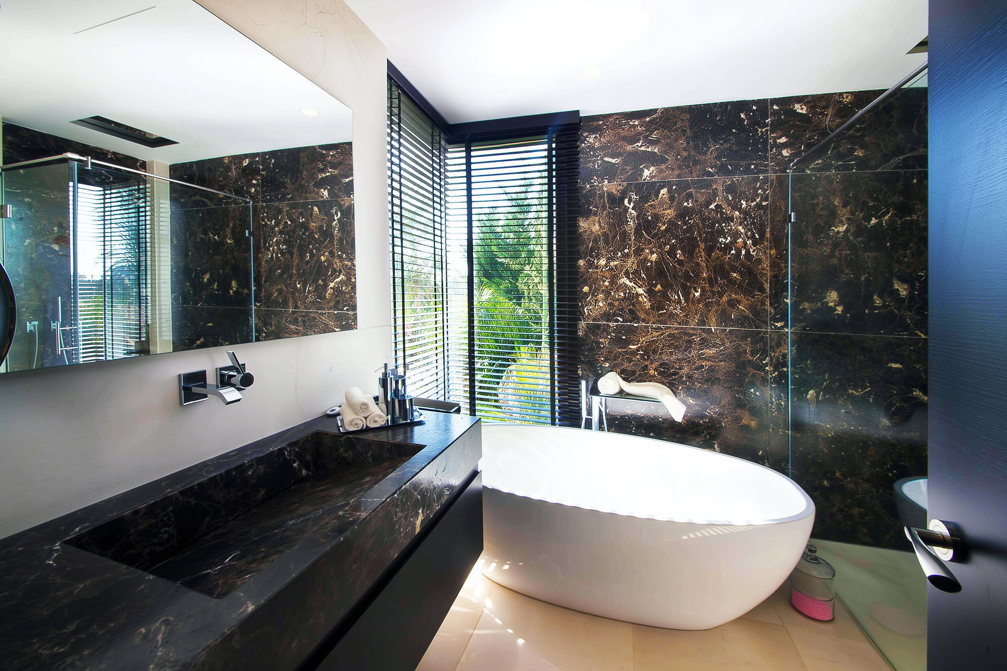 Main bathroom at Villa Tanya with freestanding bathtub, dark stone cladding and full-height glazing