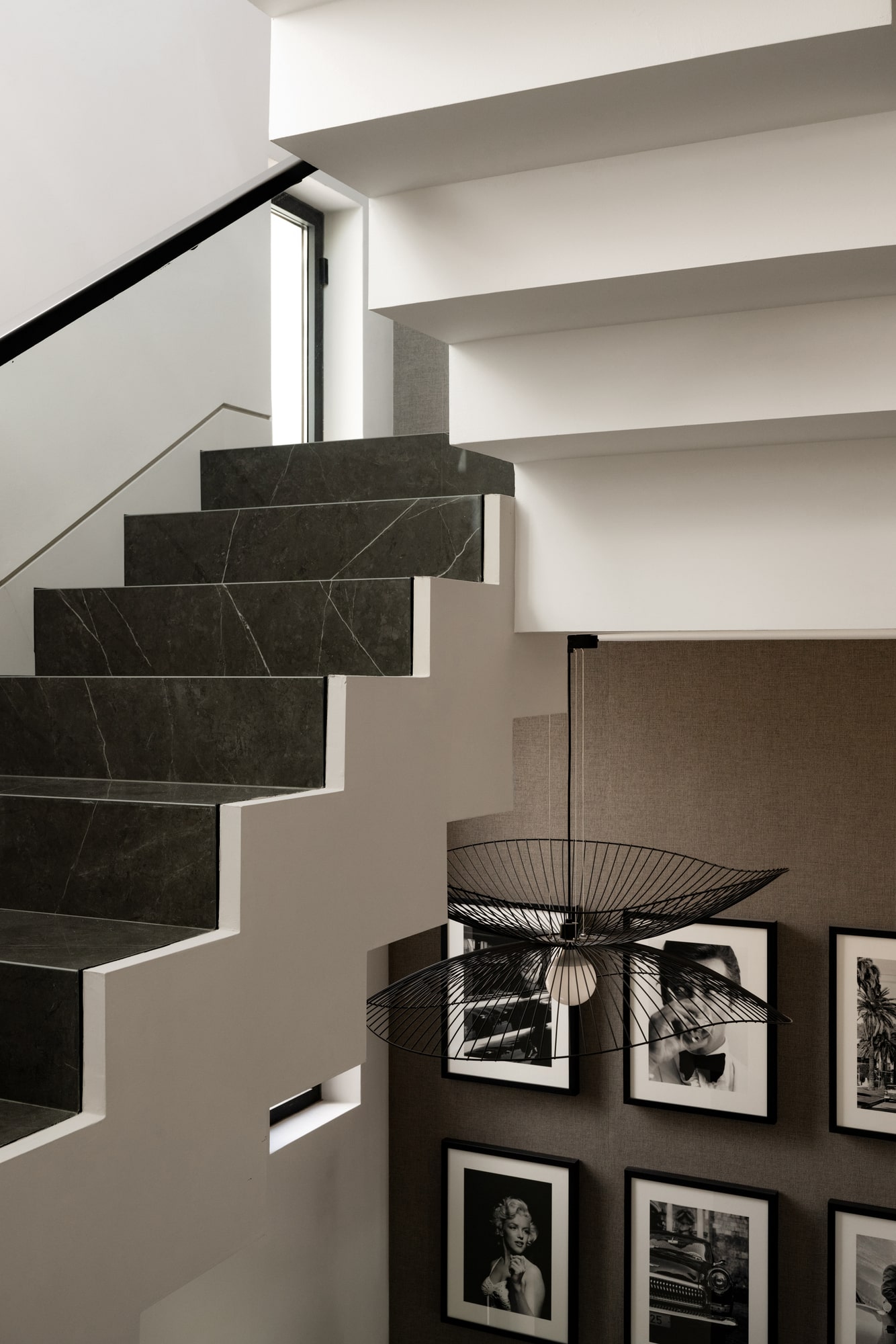 Sculptural staircase detail at Casa Velázquez with framed photography wall and natural light filtering across the steps