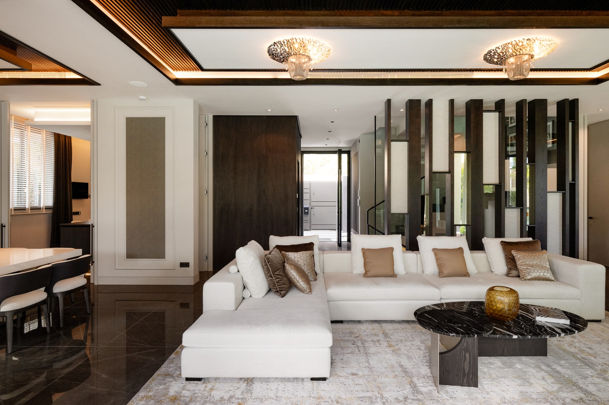 Formal lounge of Casa Velázquez with symmetrical composition, warm ceiling lighting and refined contemporary materiality