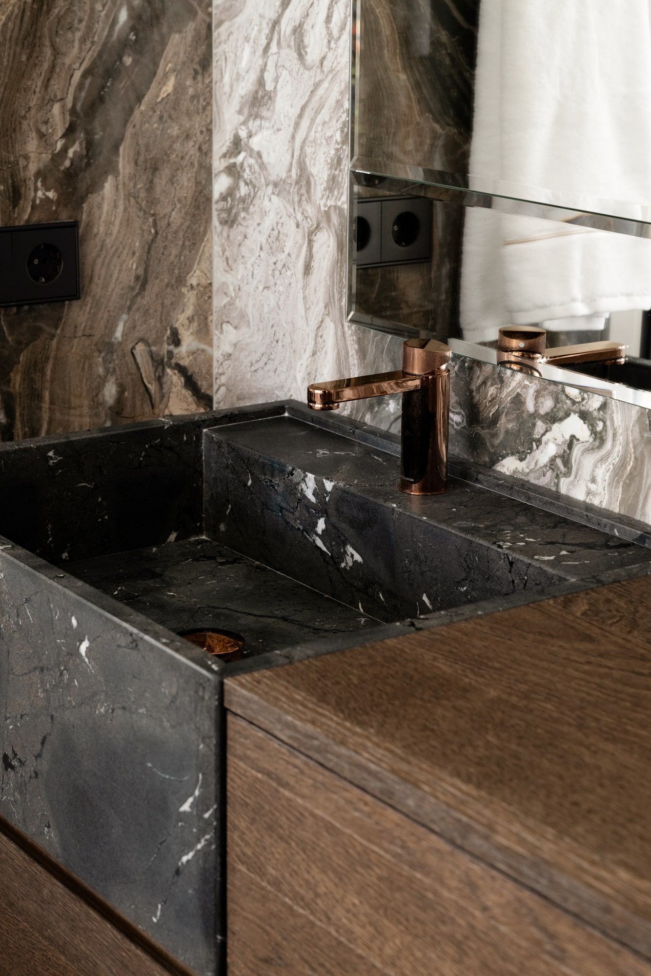 Bathroom vanity detail at Casa Velázquez with dramatic natural stone, dark basin and bespoke joinery