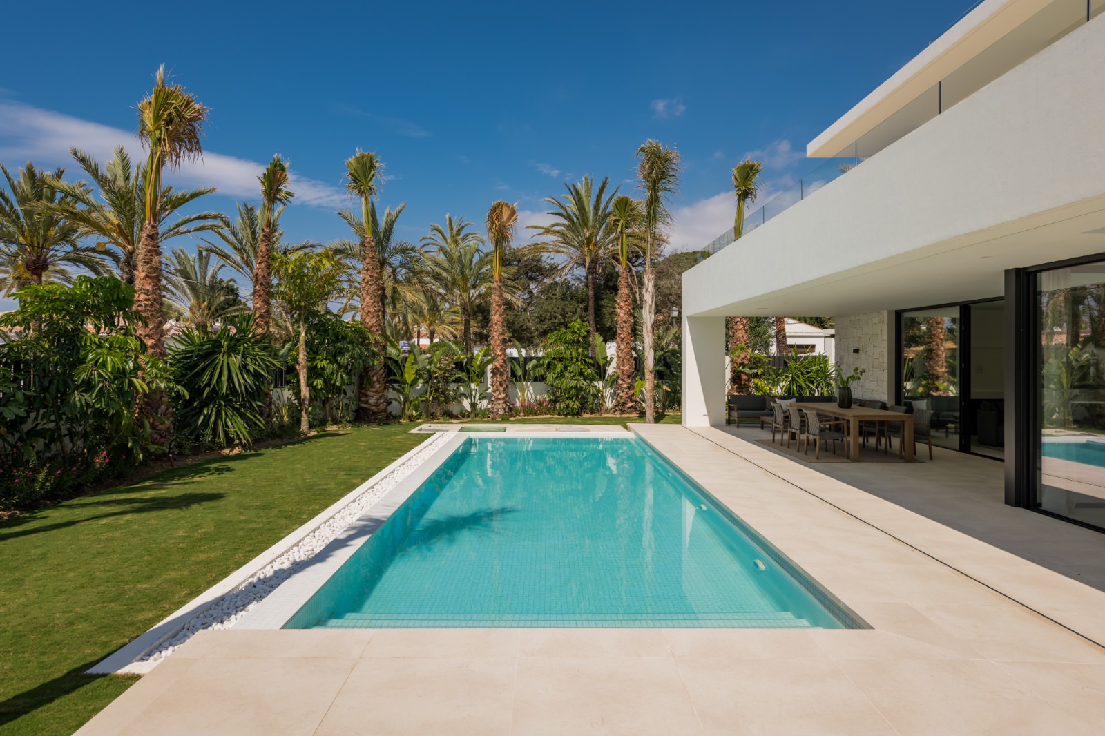 Linear swimming pool at VIDA DEL MAR framed by tropical planting, deep overhangs and white architectural volumes