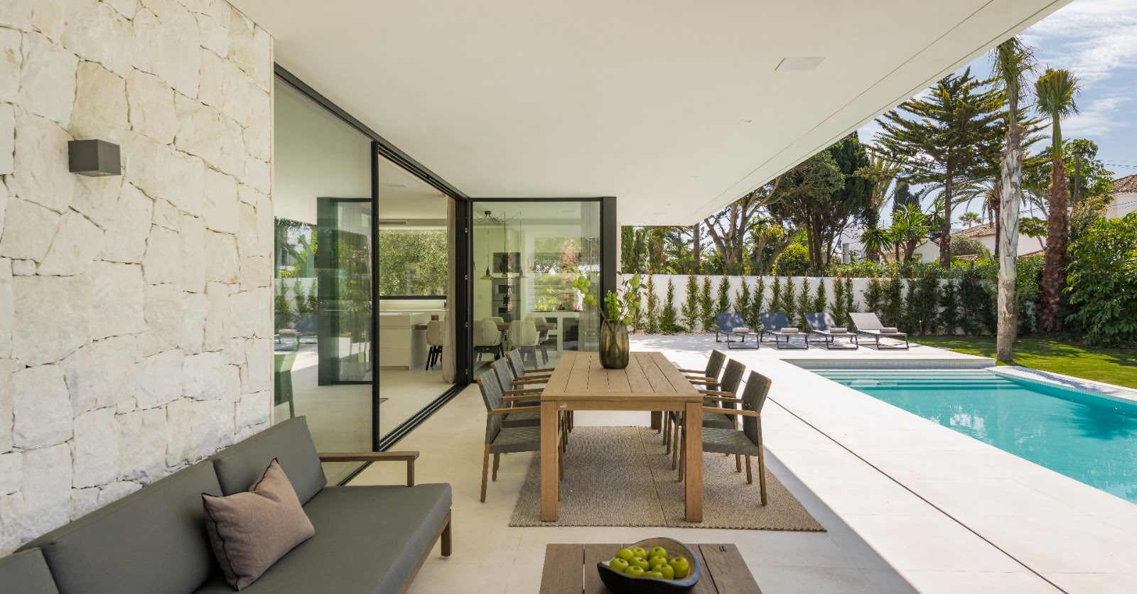 Covered outdoor lounge at VIDA DEL MAR with stone walls, integrated seating and direct views to the pool