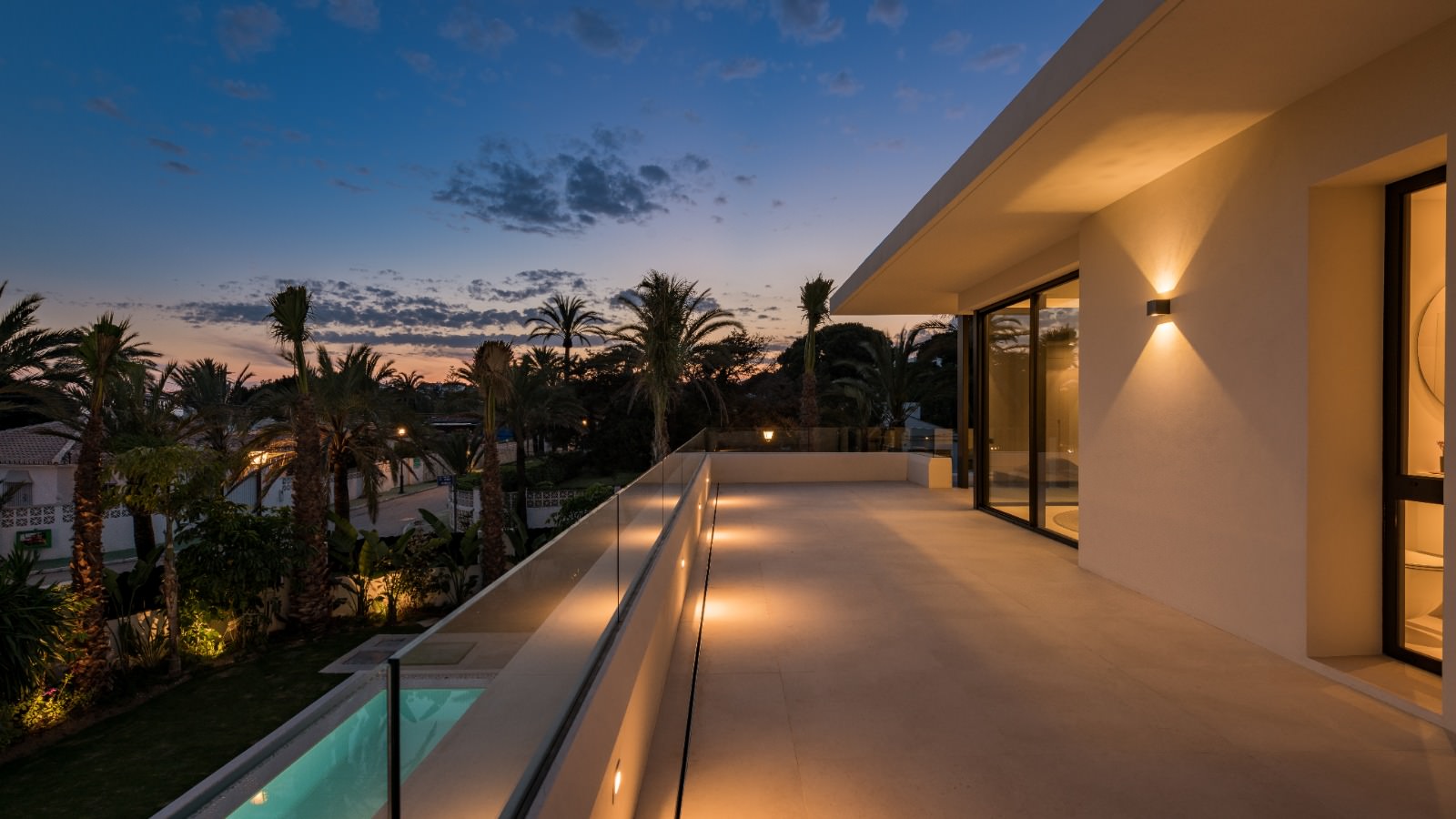 Night terrace sequence at VIDA DEL MAR with long illuminated walkway, pool edge and distant coastal atmosphere
