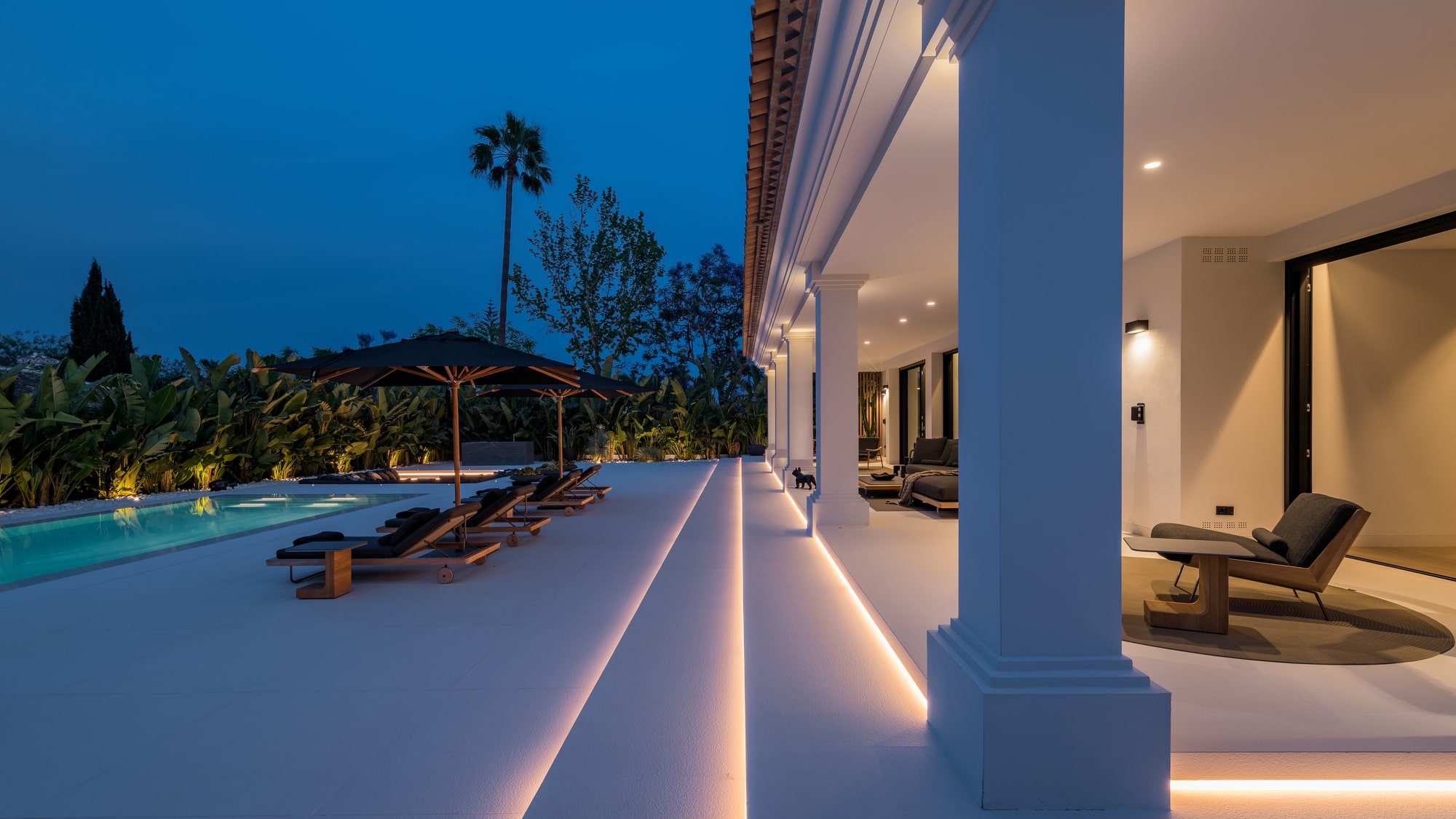 Blue-hour terrace perspective at Villa Zarina with warm interior glow, outdoor lounge continuity and elegant evening ambience