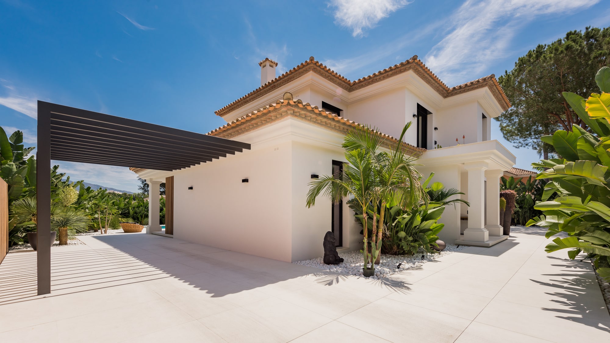 Front arrival courtyard of Villa Zarina with Mediterranean contemporary volumes, soft-toned façades and integrated garage access