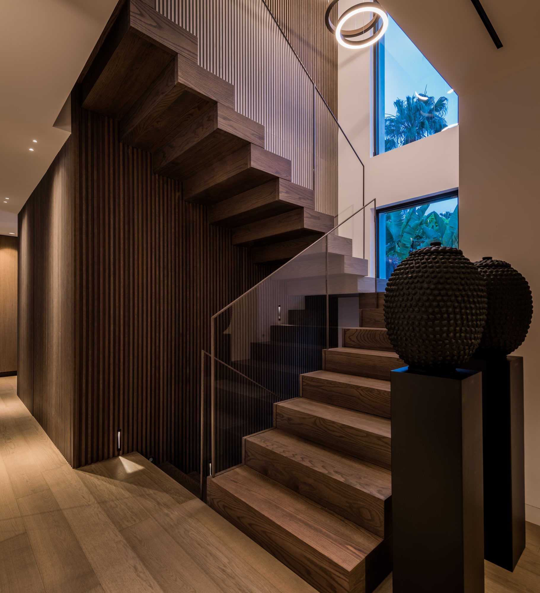 Sculptural staircase at Villa Zarina with timber cladding, ambient lighting and a dramatic vertical spatial sequence