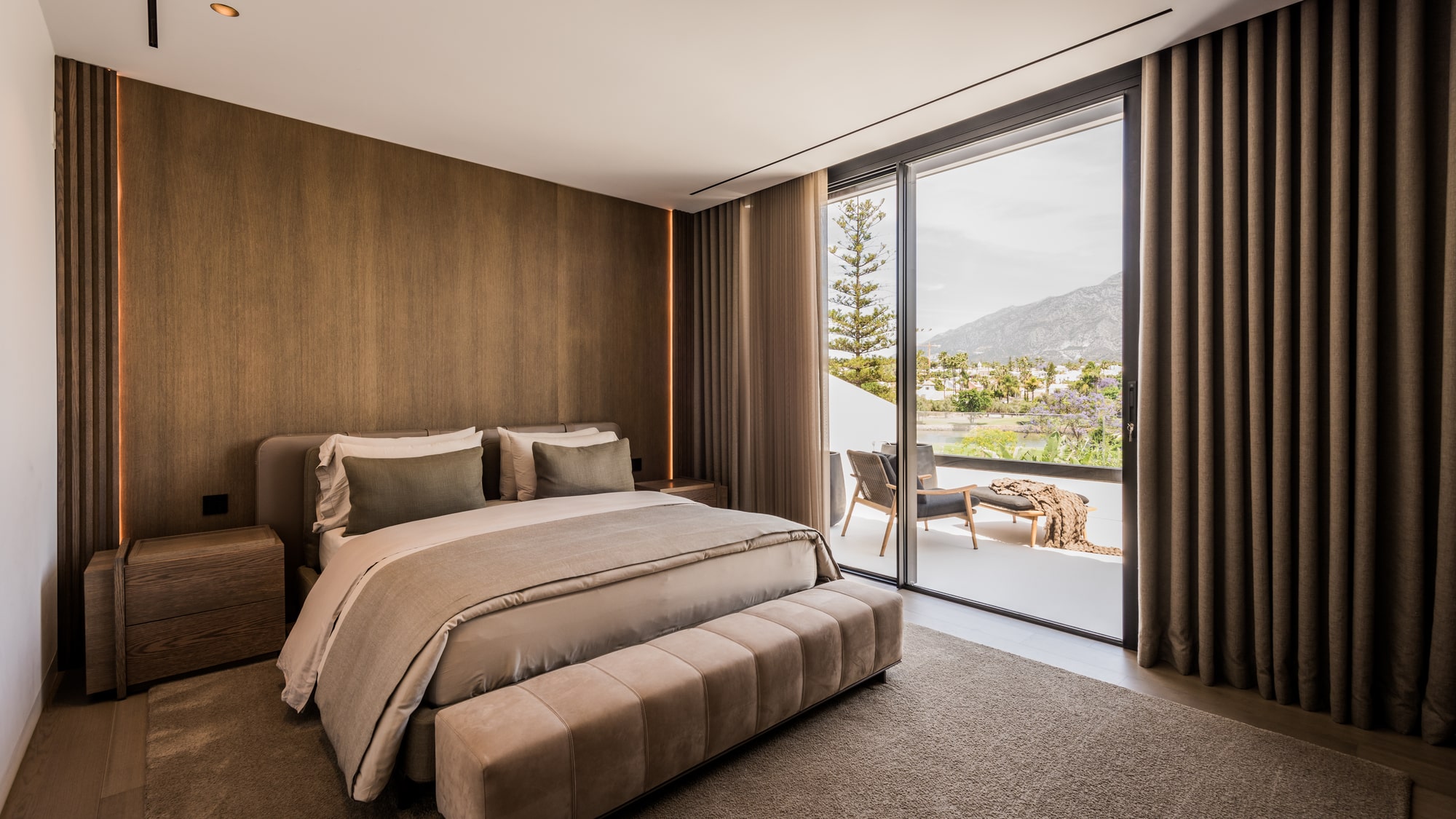 Bedroom at Villa Zarina with full-height glazing, soft neutral textiles and framed views towards the landscaped exterior