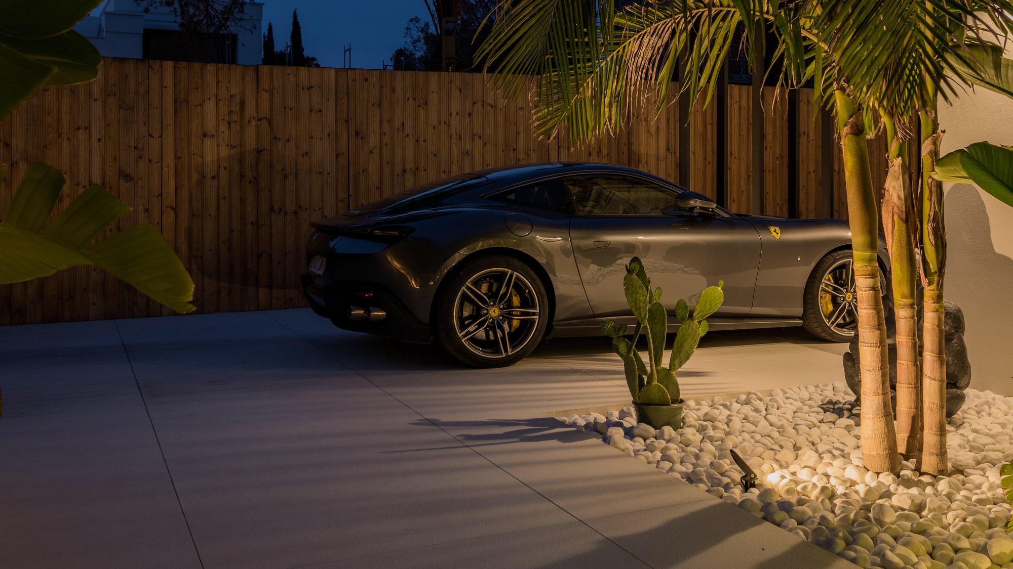 Night-time driveway at Villa Zarina with sculpted landscaping, warm perimeter lighting and luxury car arrival sequence